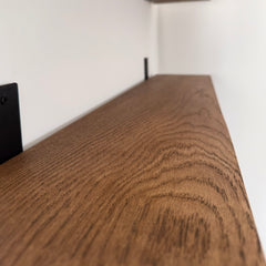 Close-up of a wooden shelf with a white wall background