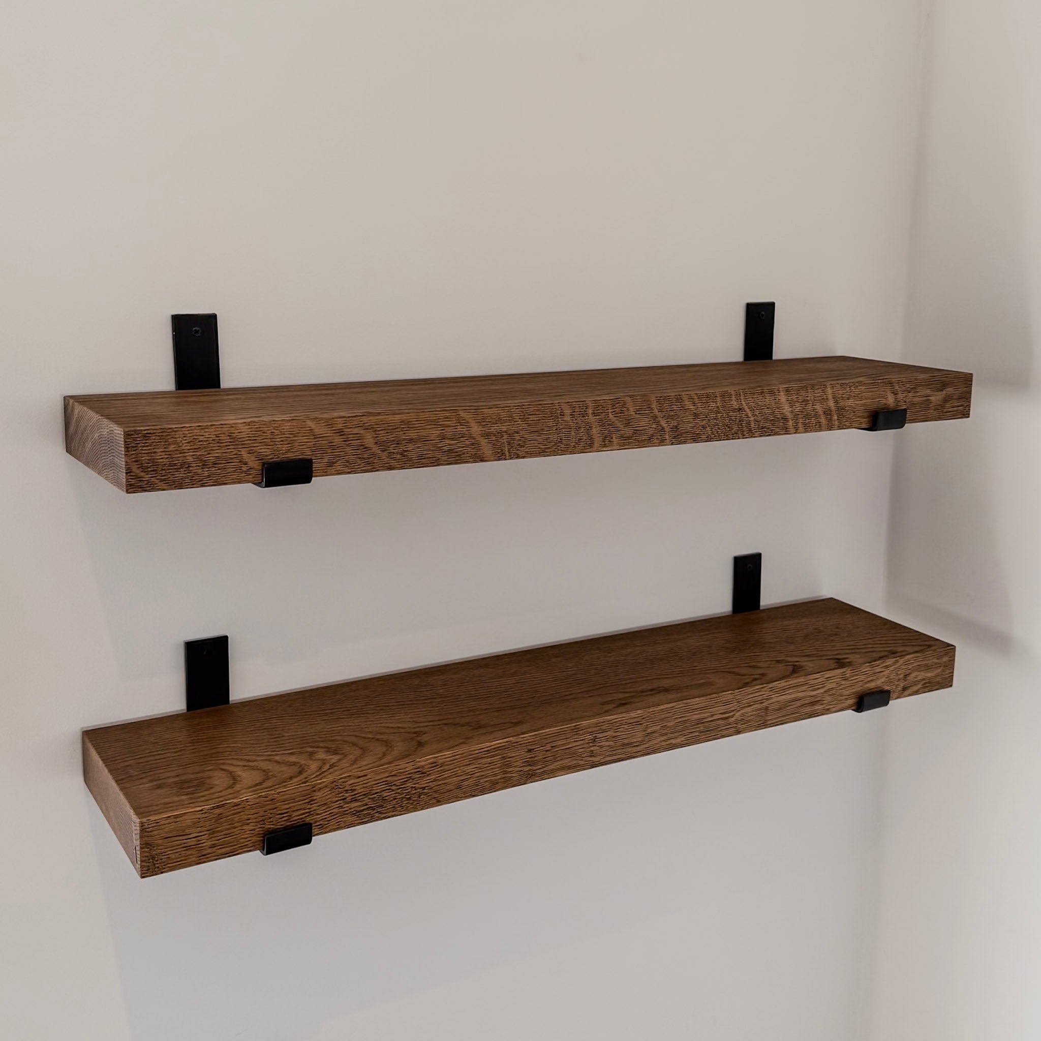 Two wooden shelves with metal brackets on a white wall.